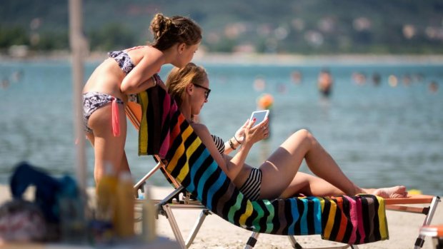 Mother and child on a beach looking at a tablet