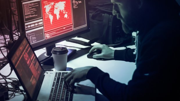 Man in front of computers in a dark room.