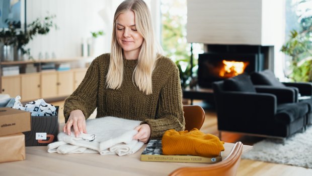 Kvinne sittende ved spisebord med esker og klær