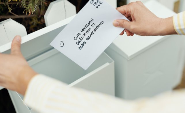 Konvolutt med adresse og digitalt frimerke puttes oppi en postkasse