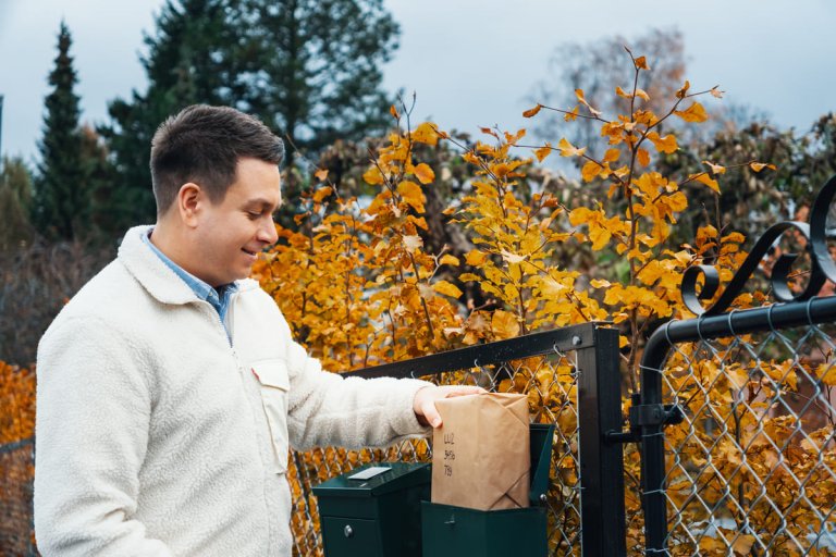 Mann legger en pakke i postkassen