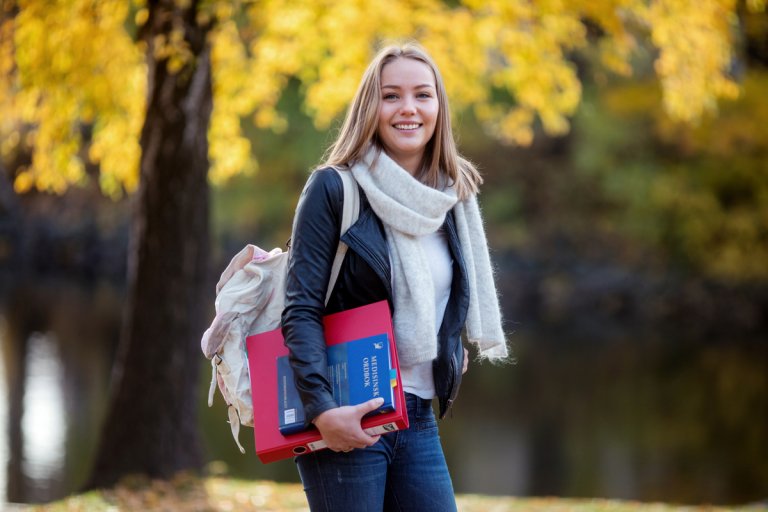 Ung kvinne med pensumbok i hendene