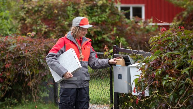 Postbud leverer i postkasse ute.